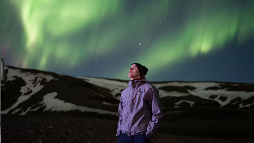 Tourist observing northern lights on a clear-sky night