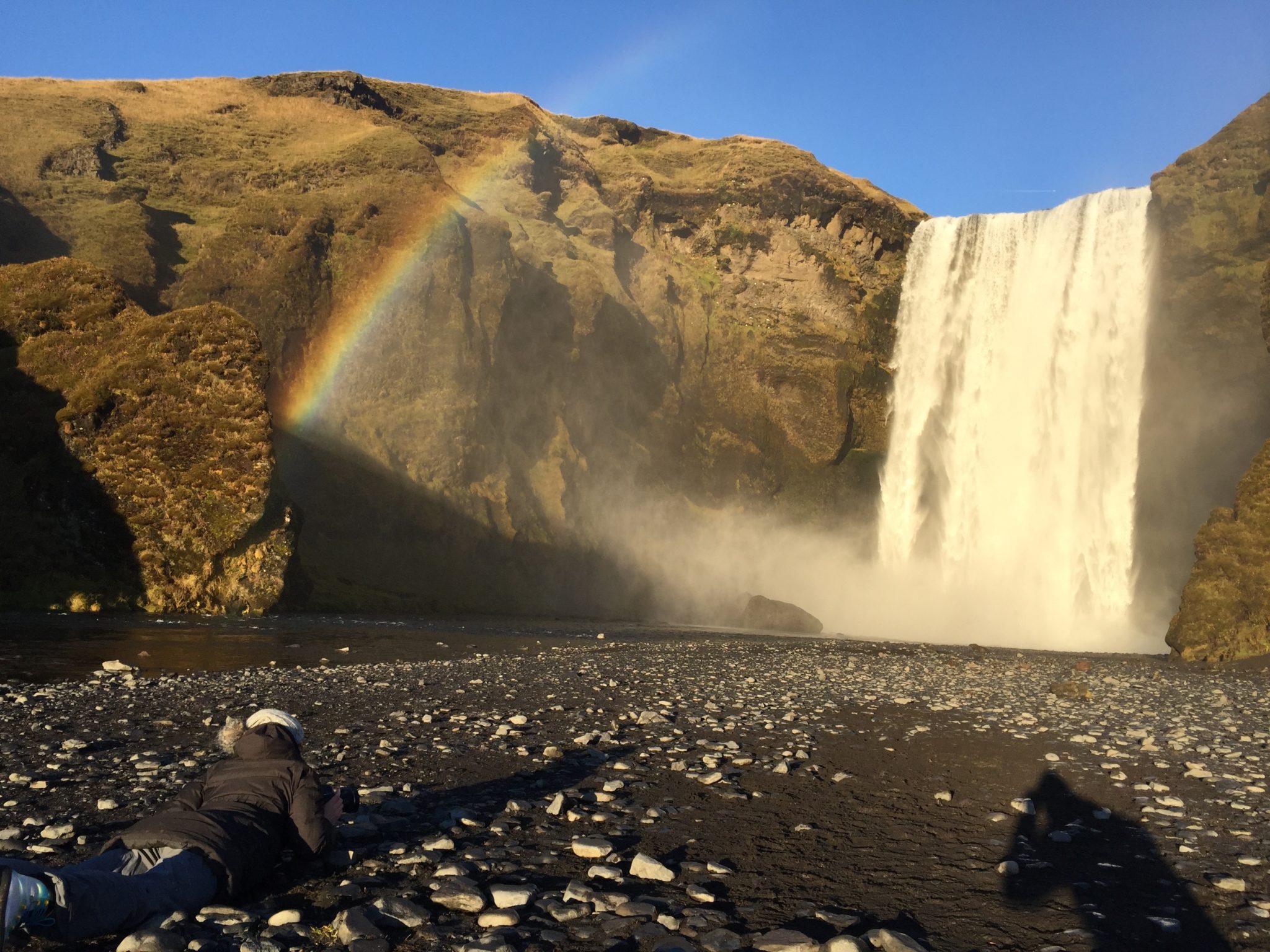 Skógafoss waterfall with a rainbow above on a sunny day
