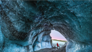 A traveller dressed in red exploring a natural ice cave