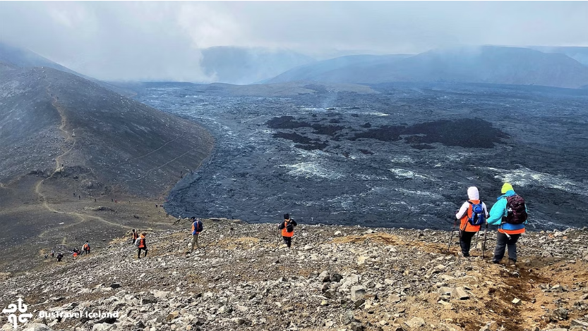 Hikers walking downhill towards the Geldingadalur volcanic site