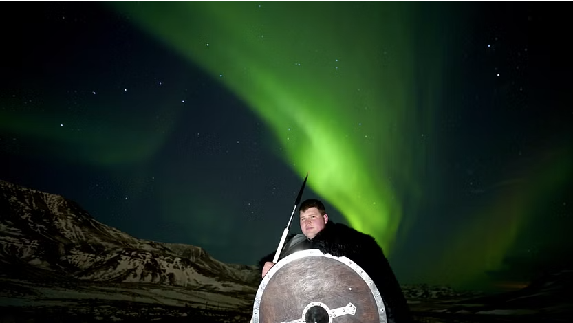Tourist disguised as a viking posing with northern lights in the background