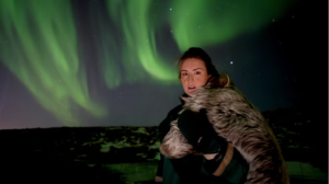 Tourist disguised as a viking posing with northern lights in the background