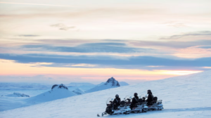 Tourists snowmobiling on a snowy mountain flanc