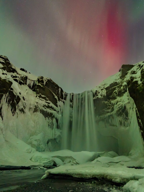 Extremely rare “blood aurora” dancing over Skogafoss