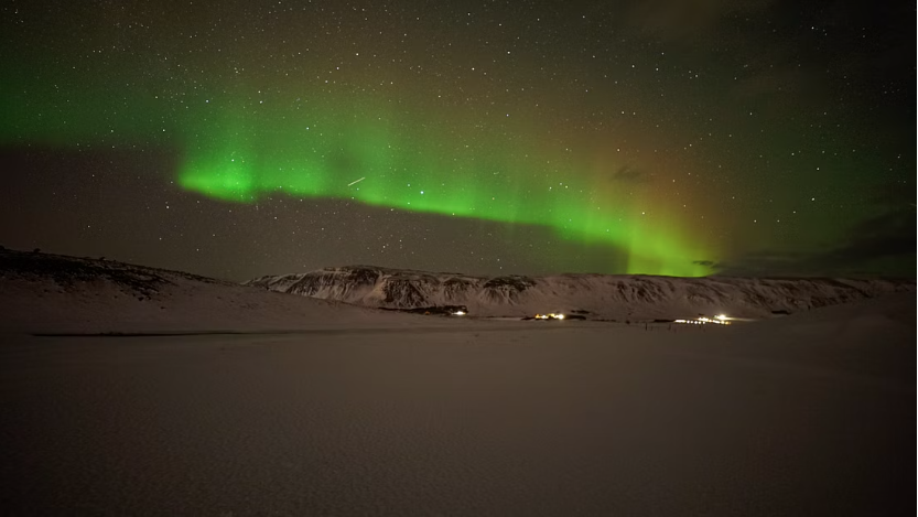 Northern lights and starry sky over a snowy mountain top