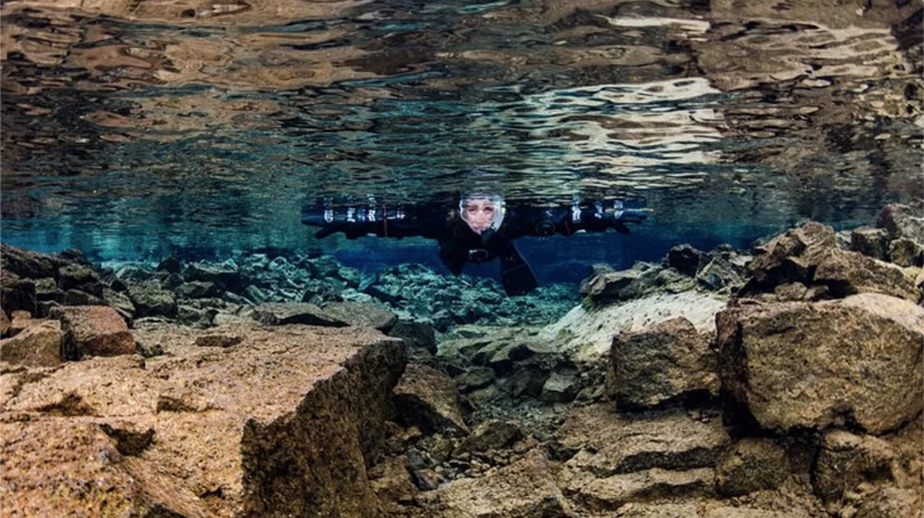 Tourists Snorkeling in shallow waters between the continents in Silfra: underwater view