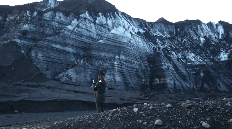 Black lava all around the glacier in the Katla area. The glacier has white, blue and black layers.