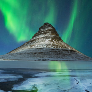 Northern Lights over Kirkjufell, reflecting in the frozen icy lake