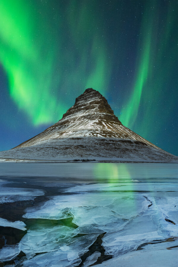 Northern Lights over Kirkjufell, reflecting in the frozen icy lake