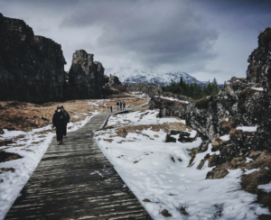 Visitors in winter clothes walking on a wooden path between the tectonic plates at Thingvellir national park