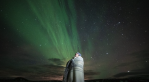 Traveller covered in a wool blanket under the northern lights