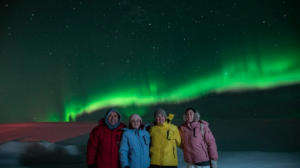 A group of travellers posing under the northern lights