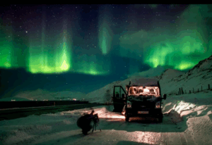 Minibus on a snowy road under the Aurora